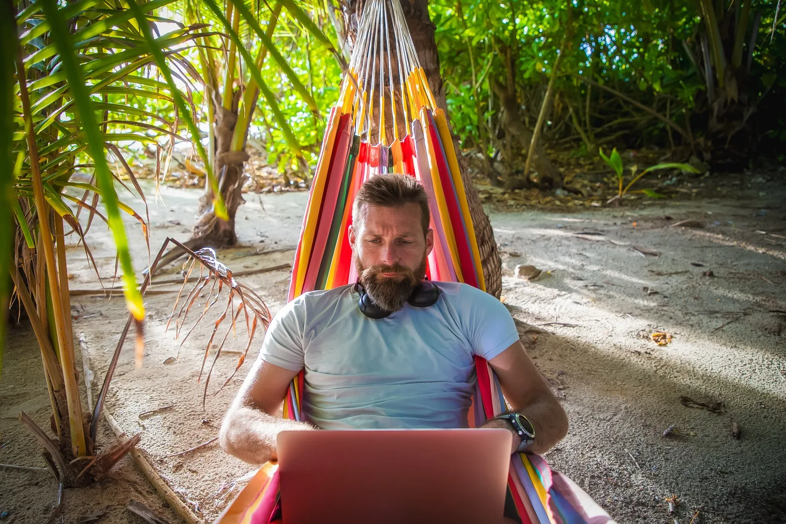 Digital nomad working on laptop at a beachside cafe with tropical surroundings